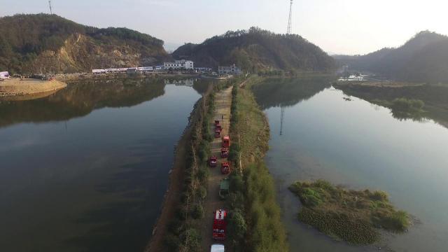 normal_457 — aerial drone shot of a clear river, red fire trucks lined along the embankment
